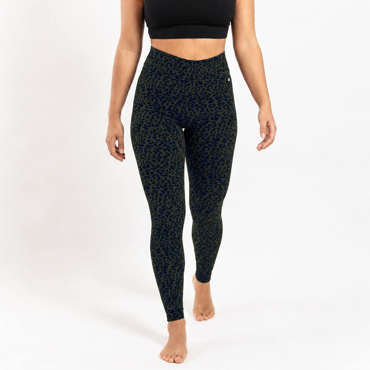 A model wearing high-waisted leggings with a dark green and black leopard print, shown from the waist down against a plain white studio background.