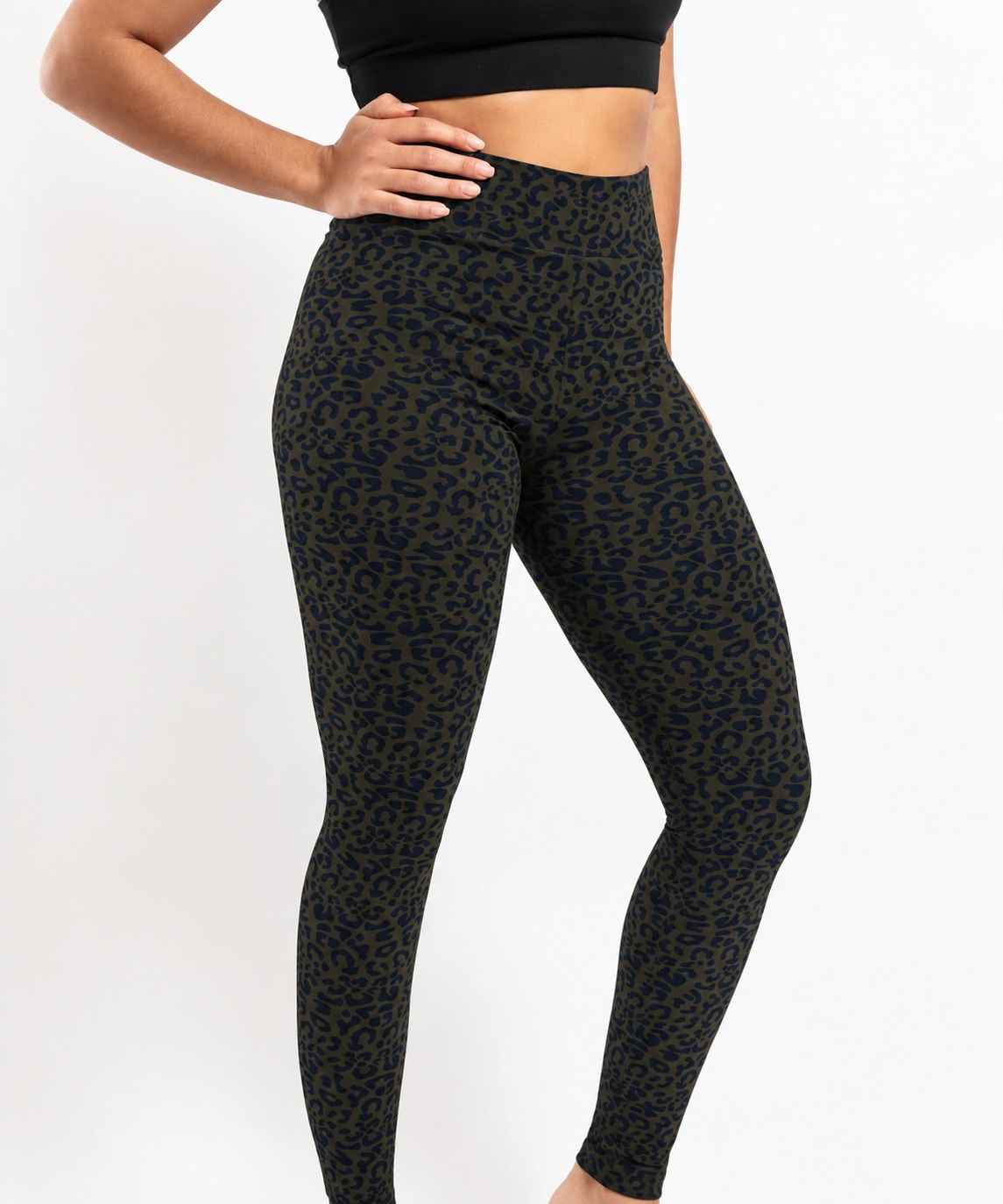 A model wearing high-waisted leopard print leggings in black and olive green, paired with a black sports bra, shown from the waist down against a plain white background.