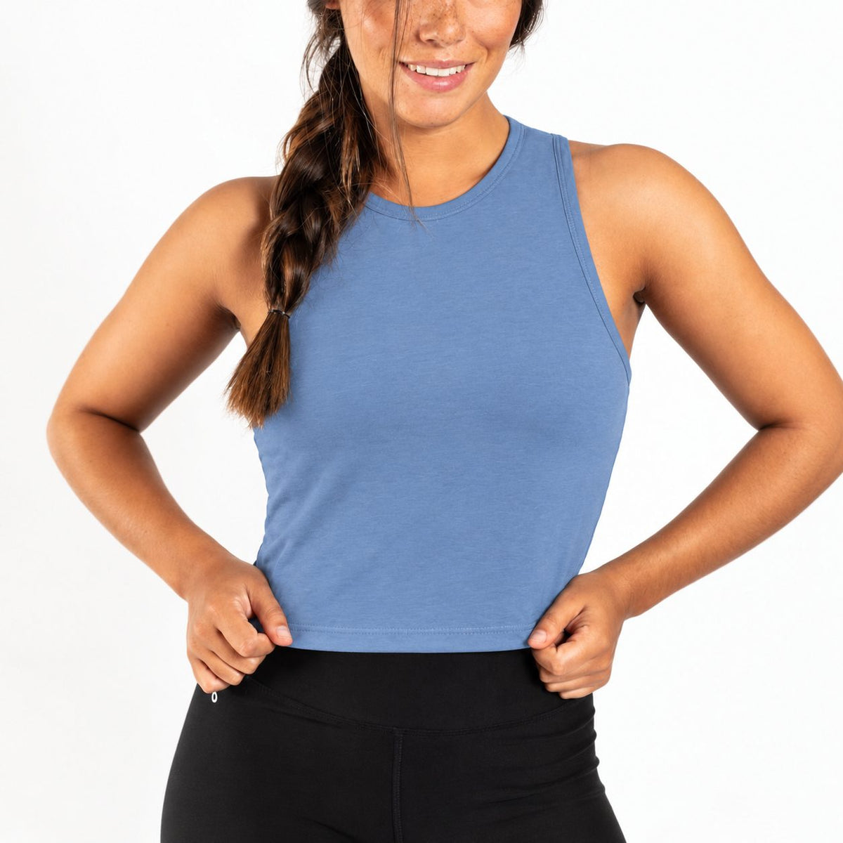 A woman wearing a sleeveless blue Organic Cotton Tank Top with built in bra and black leggings, shown from the waist up against a plain white background.