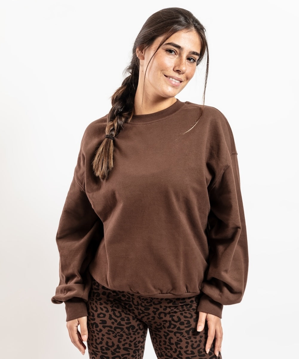 Woman wearing a brown sweatshirt and leopard print pants on a white background