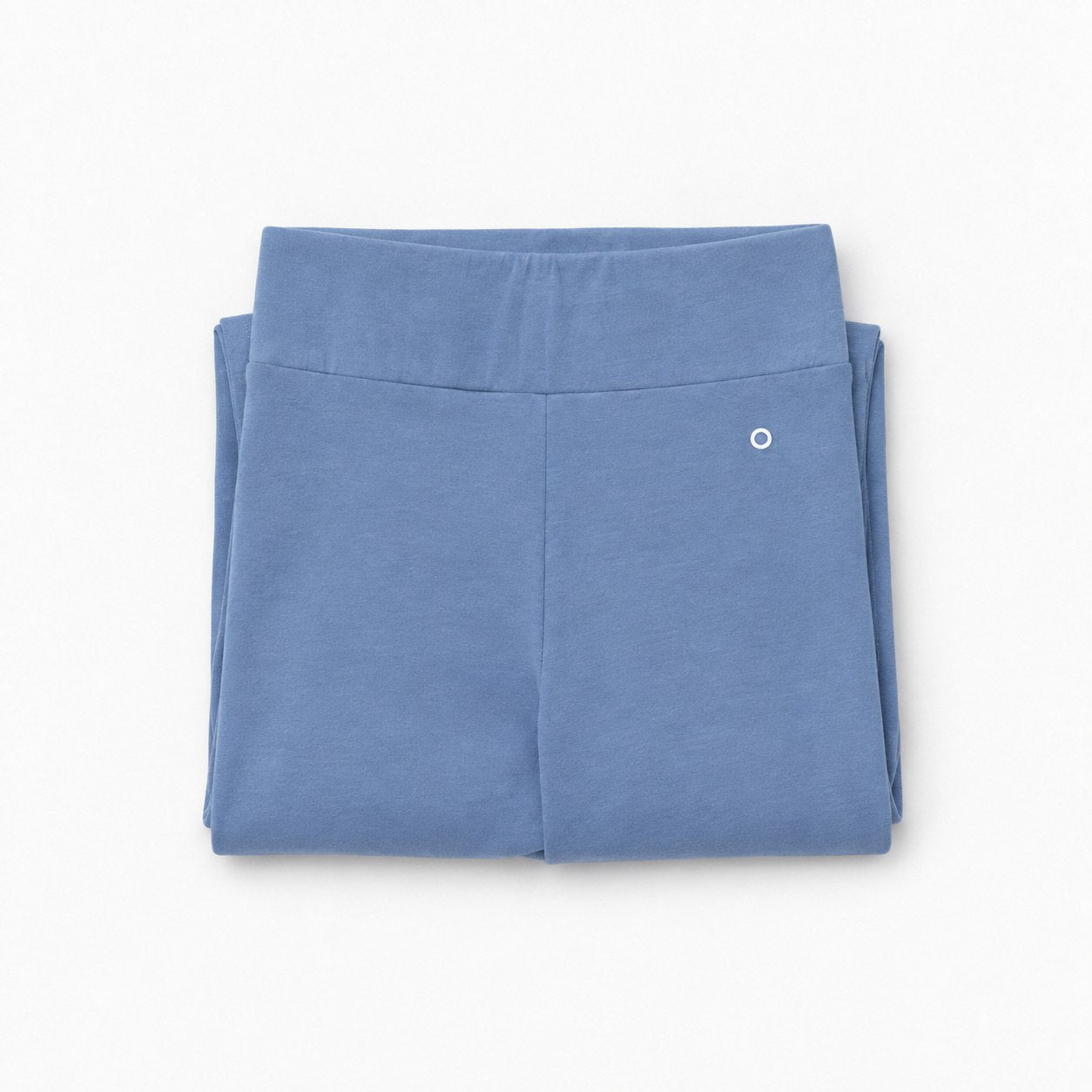 A pair of folded dusty blue organic cotton high waist leggings with a wide elastic waistband and a small white circular logo on the upper right leg, shown on a clean white background.