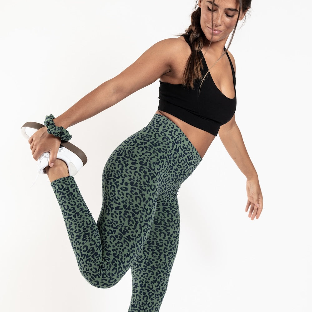 Frau dehnt sich in einer Orbasics Leo-Leggings und einem schwarzen Sport-BH