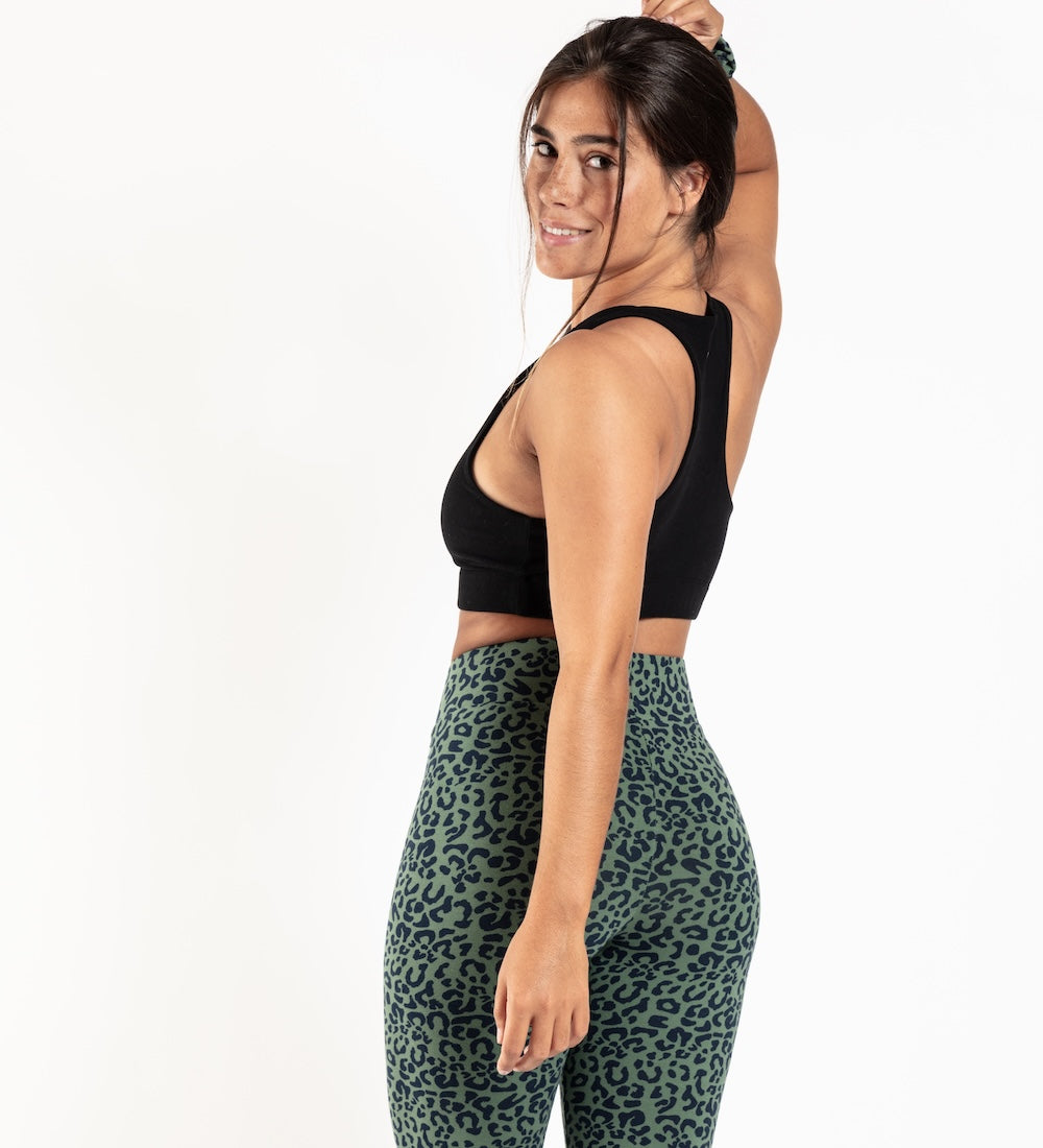 Woman wearing a black sports bra and green leo leopard print leggings 