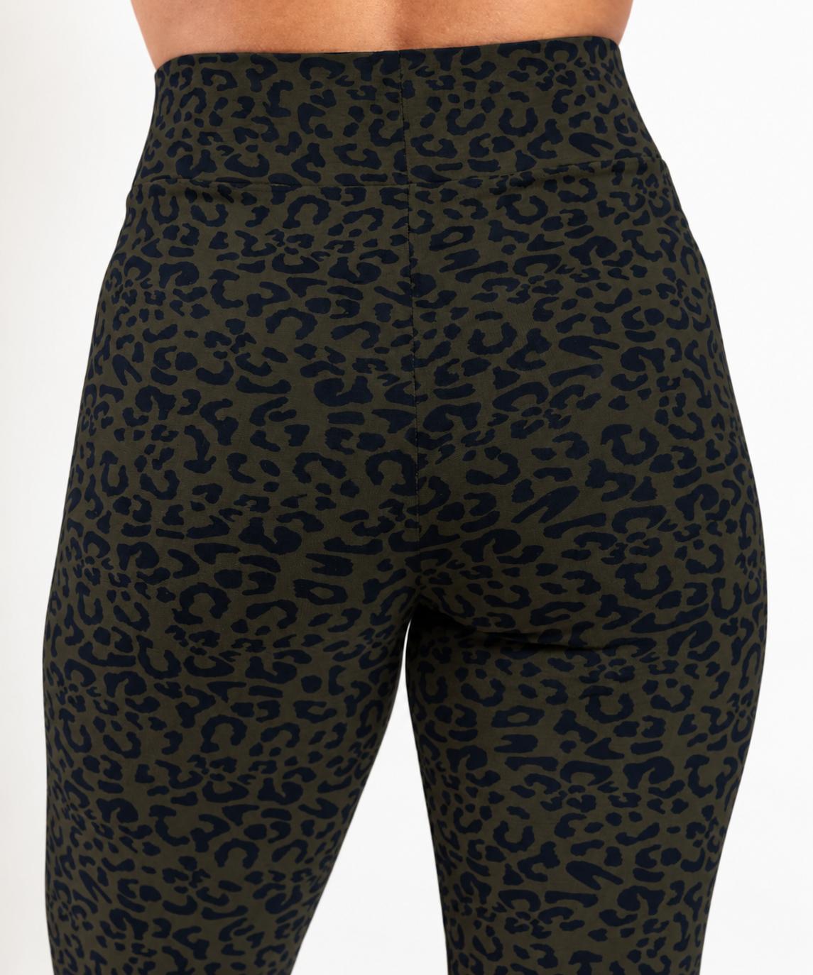 Close-up back view of a person wearing high-waisted leopard-print leggings in dark olive green and navy blue, against a plain light background.