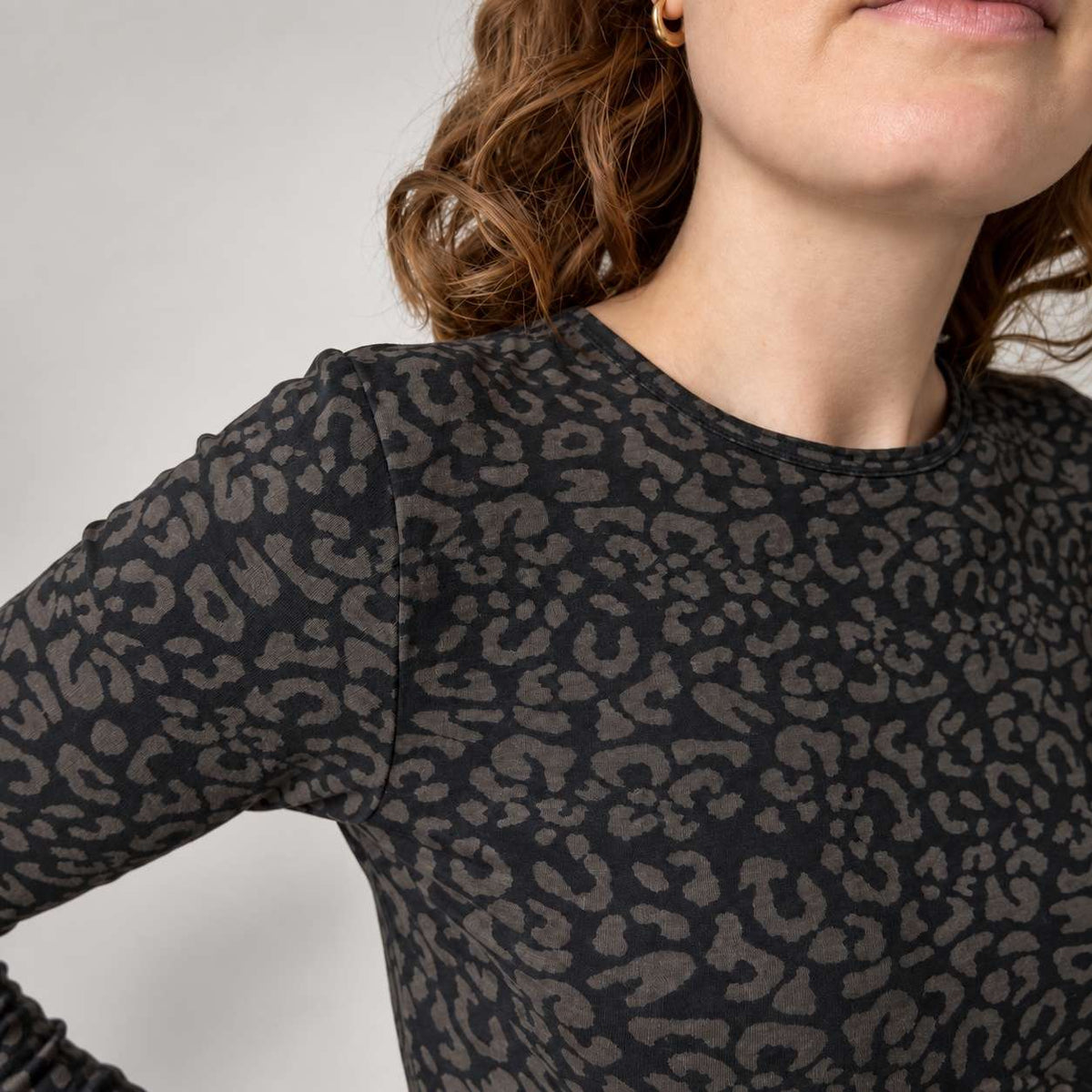 Close-up of a woman wearing a black leopard long sleeve top with a dark charcoal gray leopard print pattern.