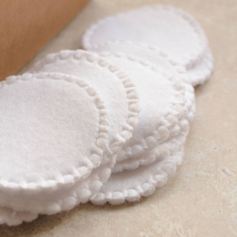 Stack of white reusable organic cotton pads on a beige surface