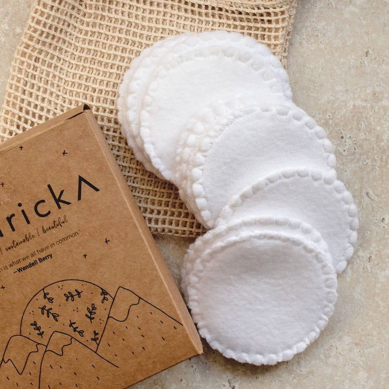 White reusable makeup pads with a brown cardboard box labeled 'ricka' on a textured surface.